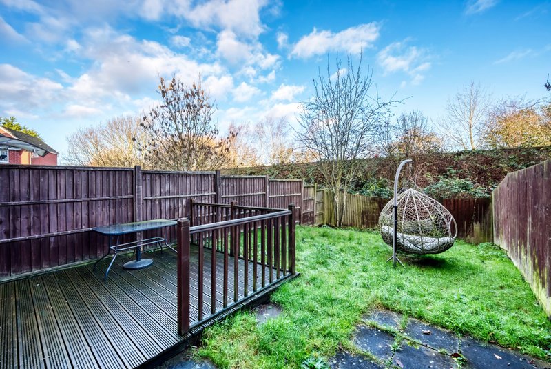 Garden space with decking, wooden fence, hanging egg chair and stream
