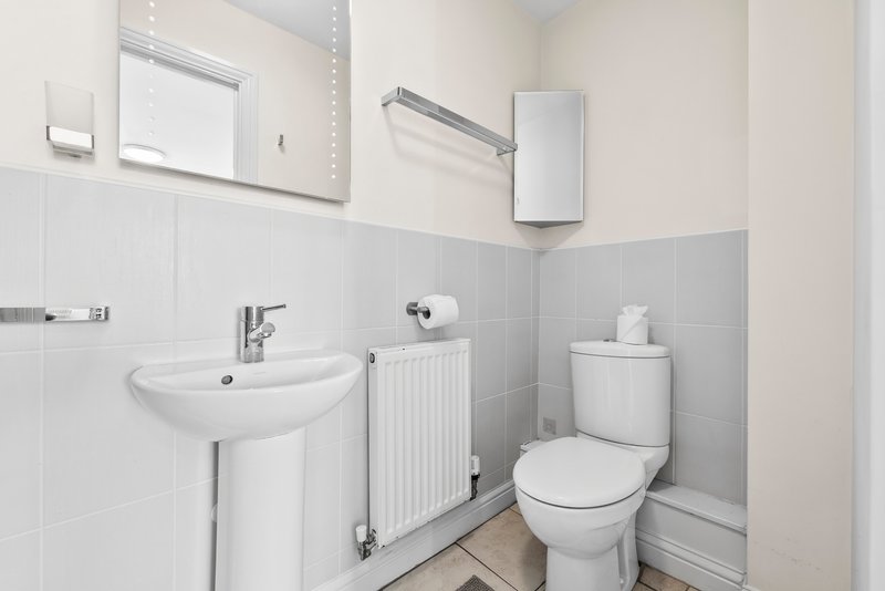 Clean white bathroom with pedestal sink, toilet, radiator and mirror cabinets