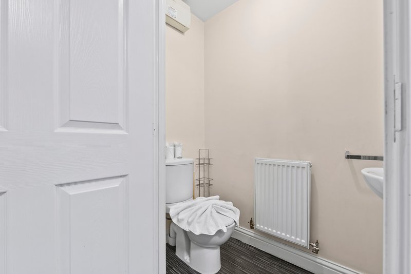 Small bathroom with toilet, radiator, towel rail and white door