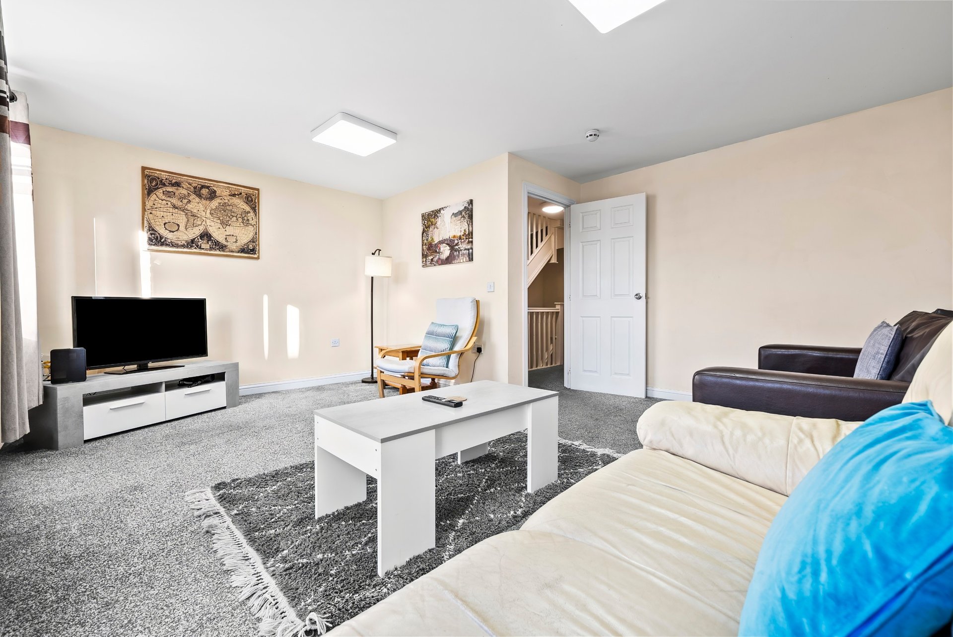 Studio apartment with bed, sofa, TV, white coffee table and cream walls