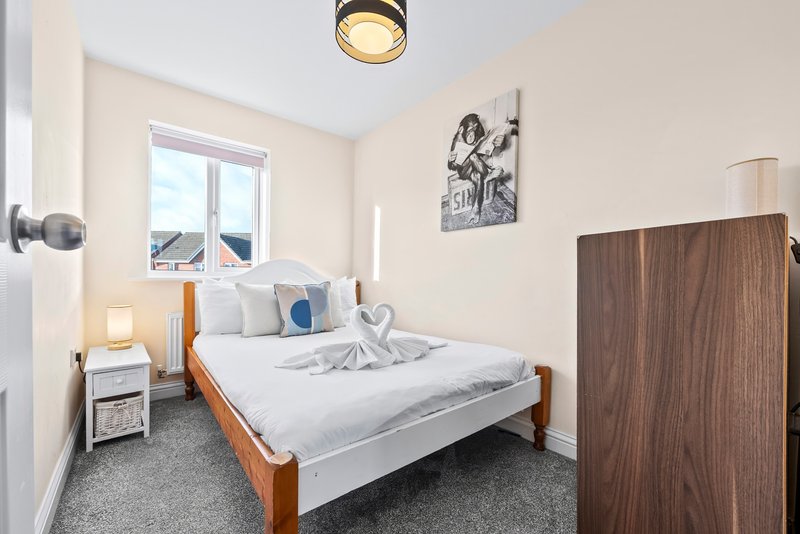 Bright bedroom with wooden bed frame, white bedding, blue cushion, and mountain view window