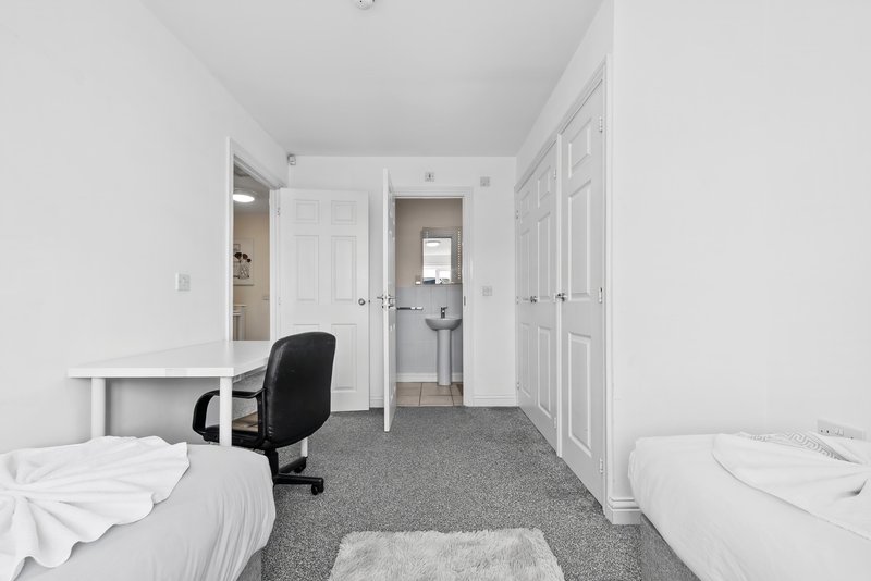Bedroom with two single beds, desk chair, wardrobe doors and entrance to ensuite bathroom