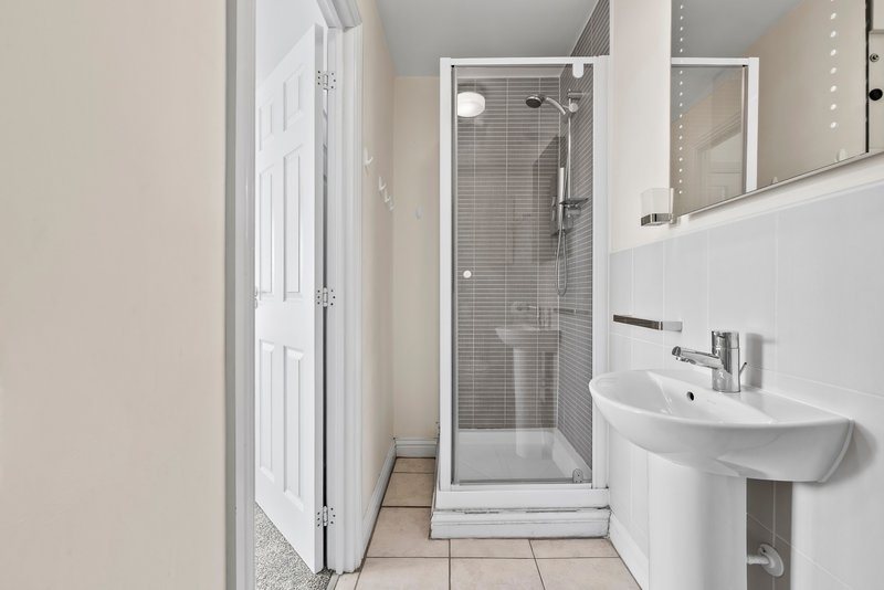 Modern bathroom with shower cubicle, white sink, mirror and tiled floor