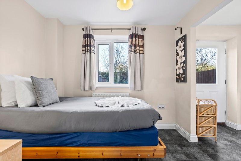 Bright bedroom with gray bed, blue base layer, striped curtains and wicker storage unit