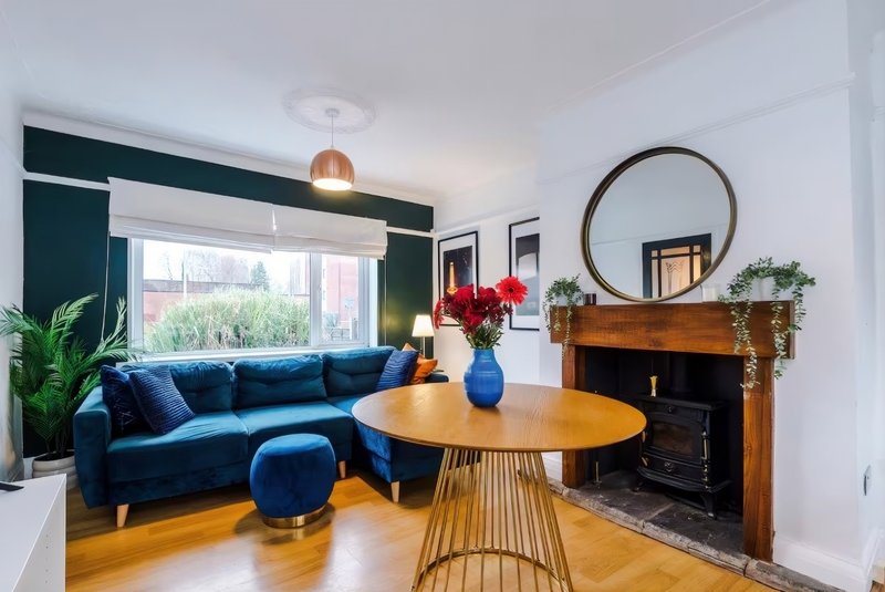 Modern living room with blue sofa, wooden dining table and round mirror