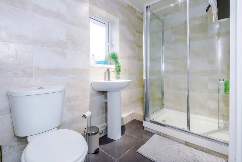 Modern bathroom with toilet, pedestal sink, shower enclosure and heated towel rack. Toiletries supplied