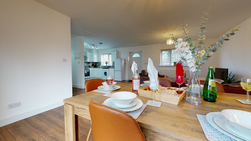 Open-plan dining and kitchen area with wooden table, place settings, and decorative items