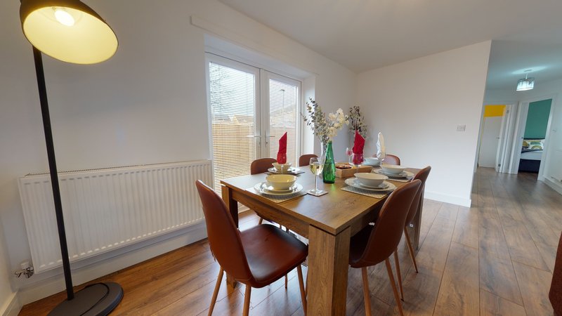 Dining room with wooden table, brown chairs, floor lamp and garden view windows