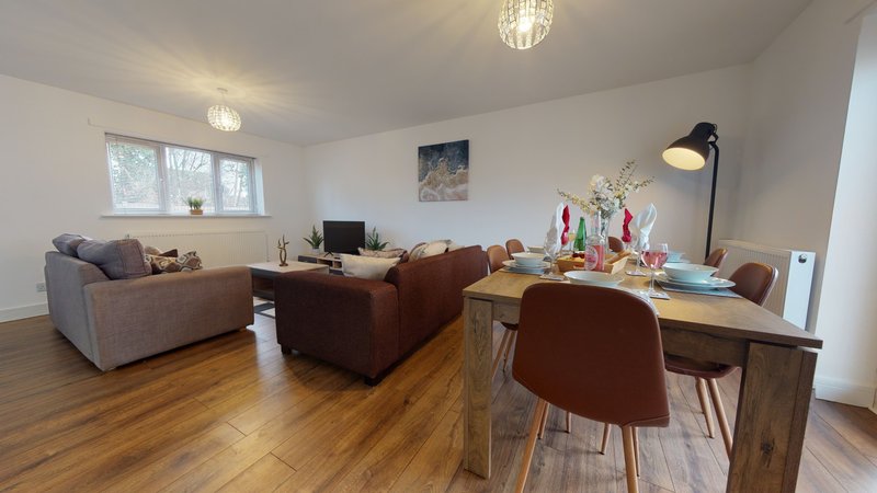 Open-plan living area with sofa, desk, wooden flooring and ceiling lights