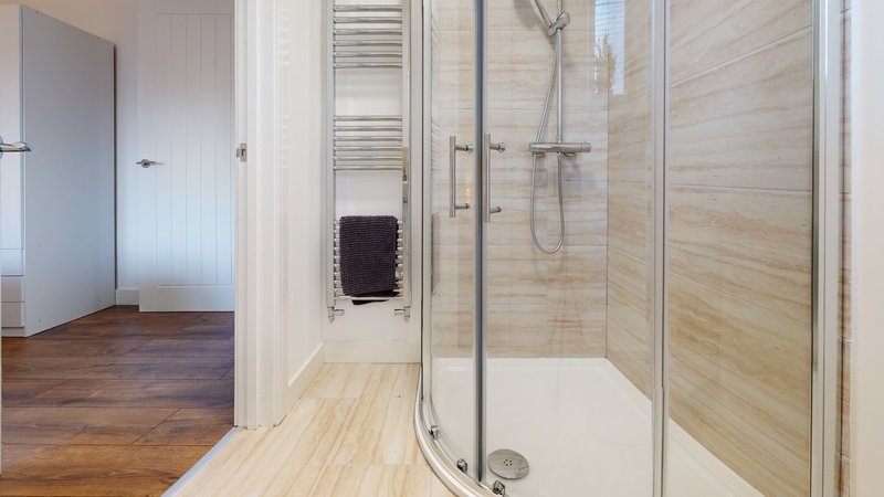 Modern bathroom with walk-in shower, white towel radiator and wooden-effect wall tiling