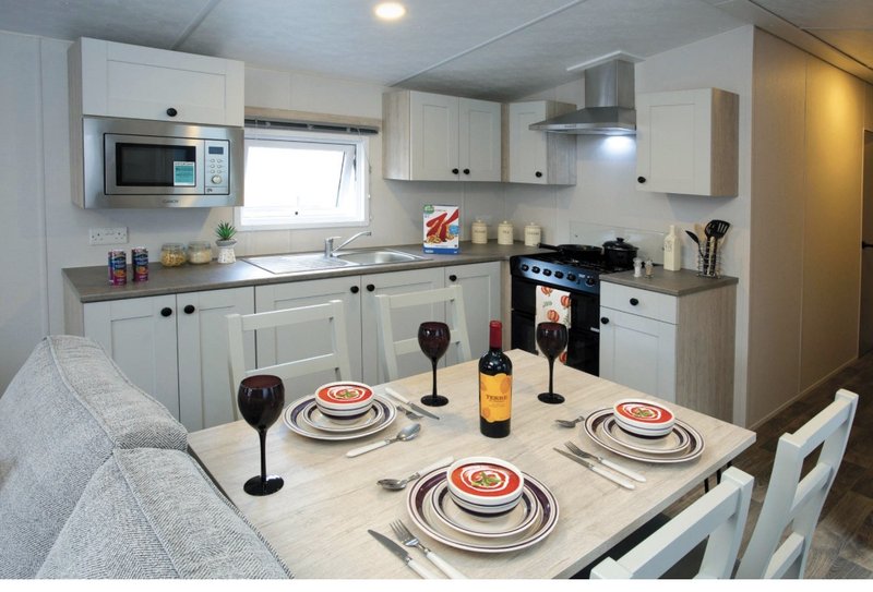 Open-plan kitchen and dining area with white cabinetry, dining table set for three, and stainless steel appliances