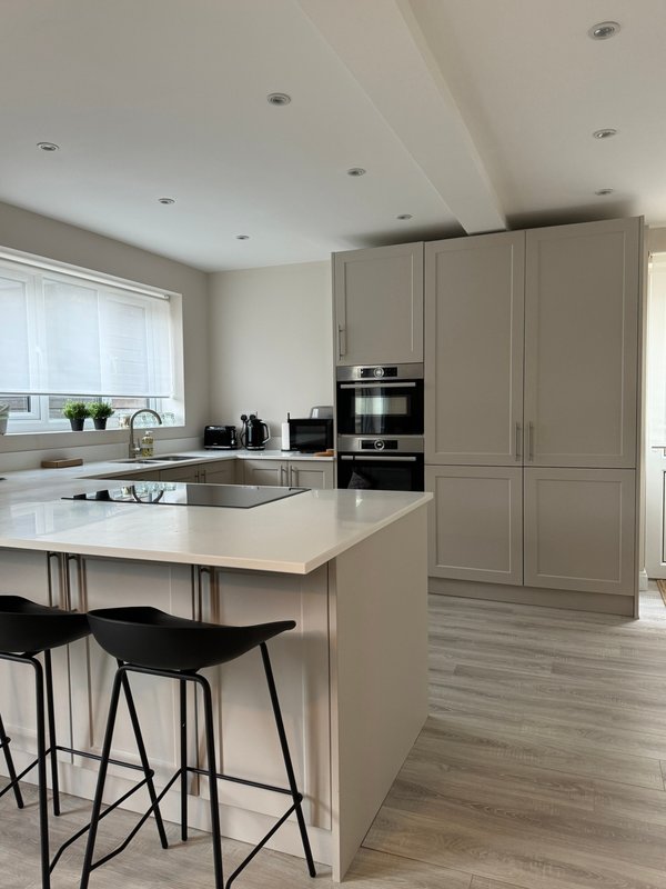 Modern kitchen with cream cabinetry, white countertops, island seating and built-in appliances