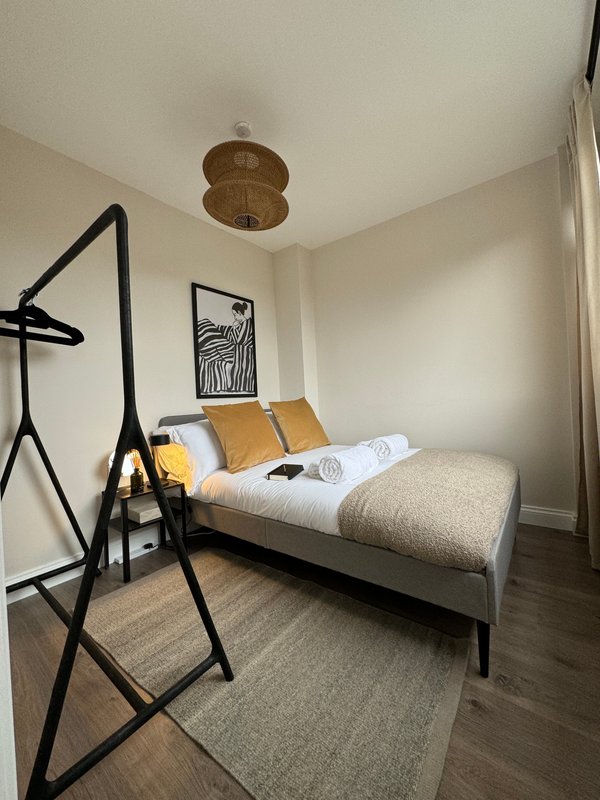 Bedroom with gray bed, black frame, woven pendant light, wall art and cushions