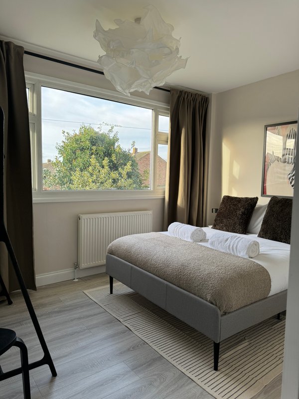Bright bedroom with double bed, window overlooking trees, wooden flooring and neutral decor