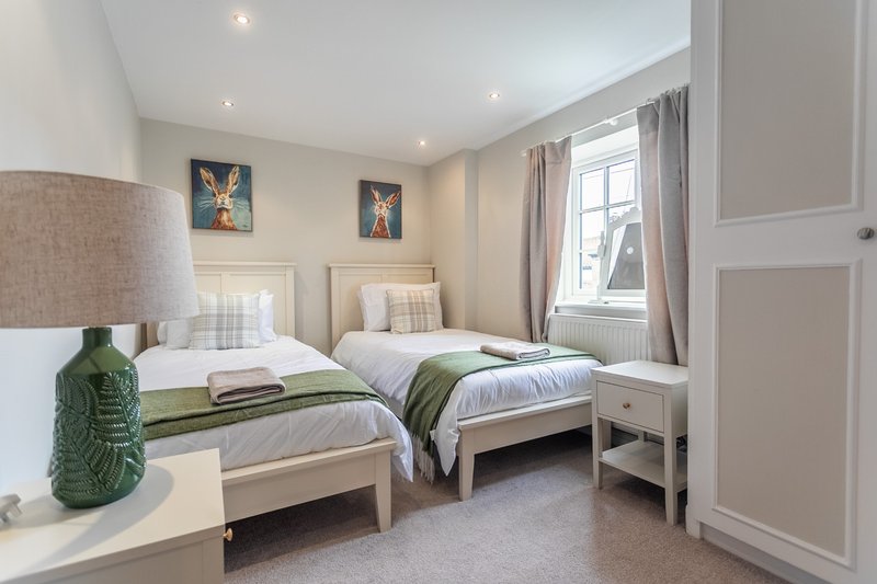 Bright twin bedroom with two single beds, bedside table, lamp and window