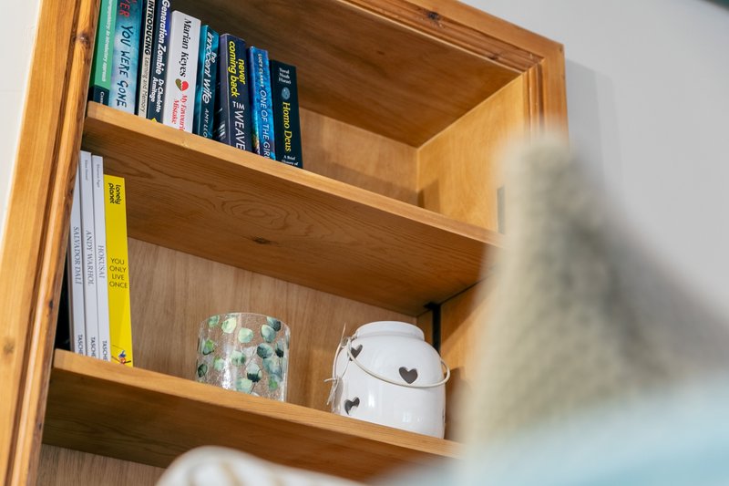 Wooden bookshelf with books, decorative items, and white storage container