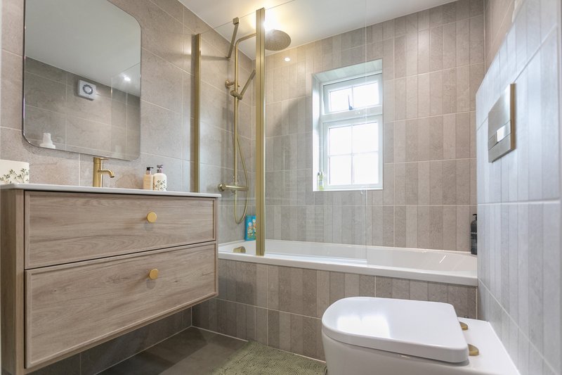 Modern bathroom with vanity, mirror, shower enclosure, toilet and window