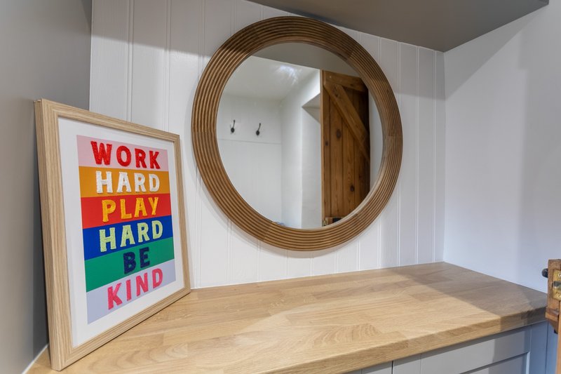 Wooden shelf with round mirror and framed motivational poster artwork