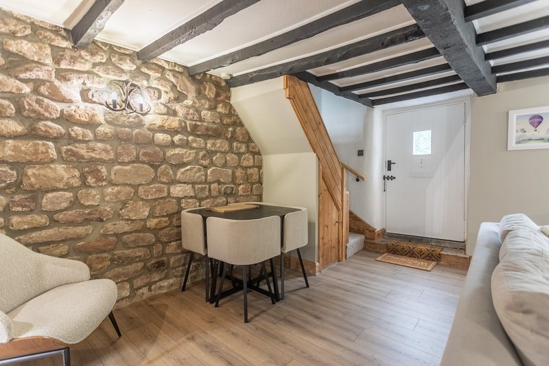 Stone-walled room with exposed beams, dining table, seating, and white door