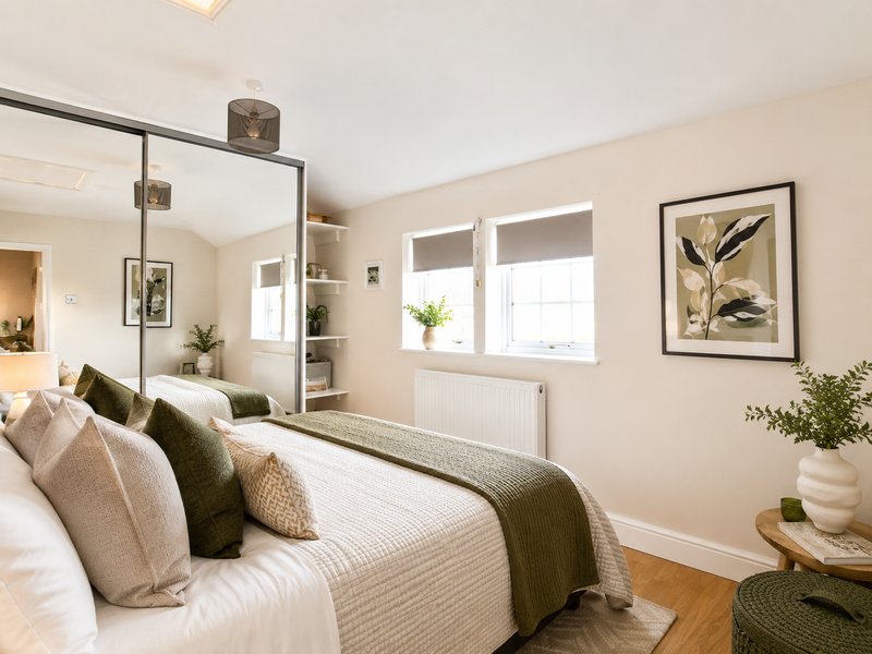 Bright bedroom with double bed, mirror wardrobe, windows, framed wall art and potted plants