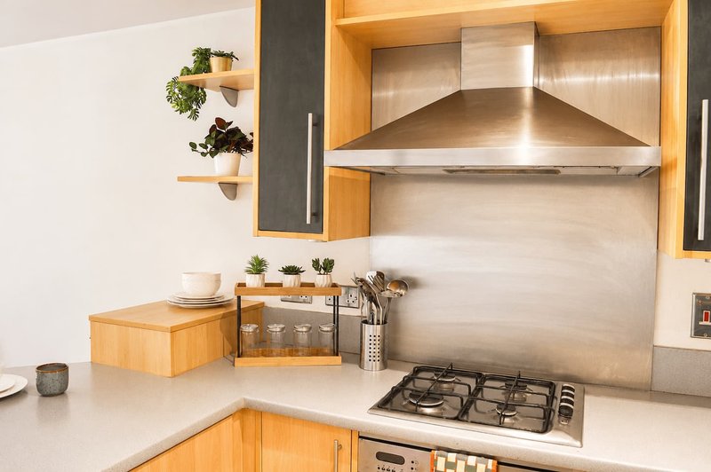 Modern kitchen with wooden cabinets, stainless steel range hood and gas cooktop, white countertop