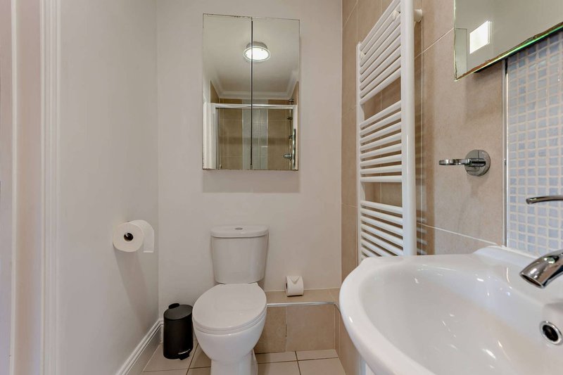 Bathroom with toilet, round white sink, mirror, heated towel rail and shower enclosure