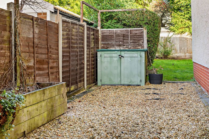 Garden with wooden and green fencing, gravel ground, and planted borders
