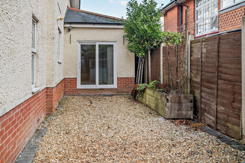 Rear garden patio with gravel surface, wooden fence, and access to house extension