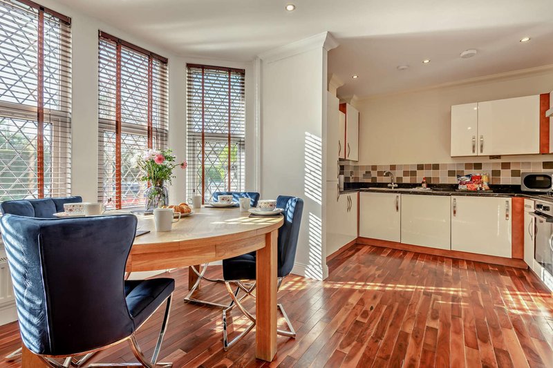 Open-plan kitchen and dining area with wooden table, blue chairs, and modern appliances