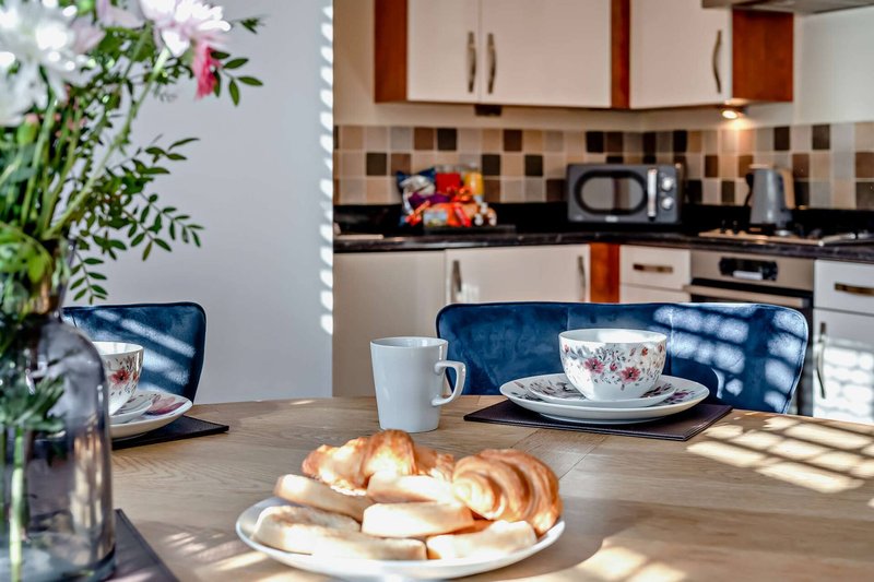 Modern kitchen-diner with wooden table, blue chairs, fresh flowers and croissants