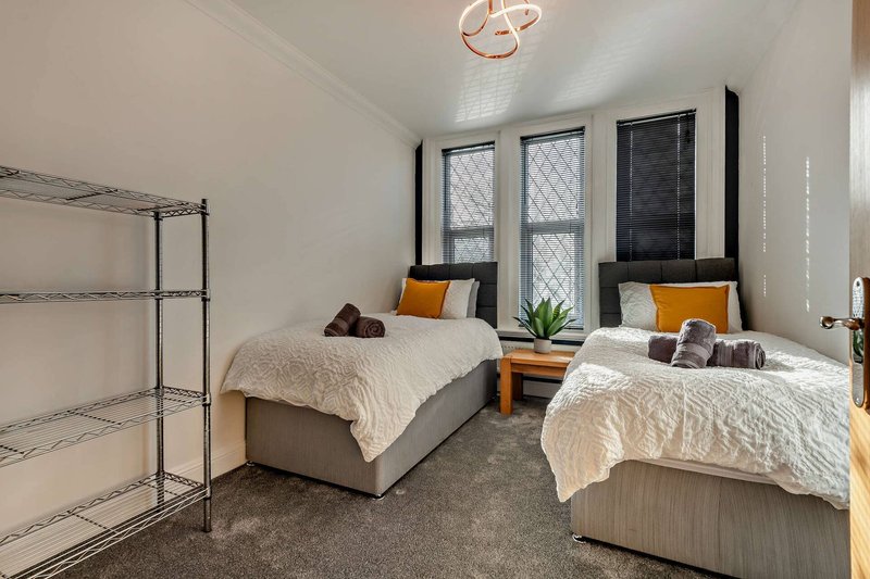 Shared bedroom with two single beds, shelving unit, windows and potted plant