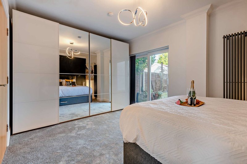 Modern bedroom with double bed, mirrored wardrobe, ceiling light and garden view