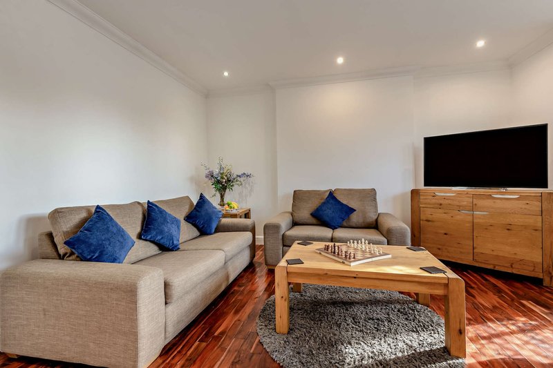 Modern living room with beige sofas, blue cushions, wooden coffee table and television