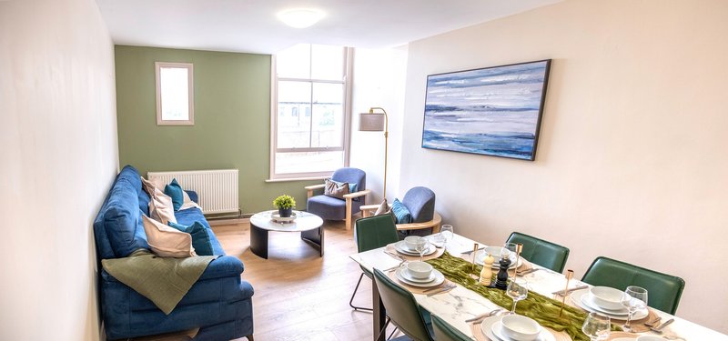 Bright living room with blue sofa, dining table, artwork and window with natural light