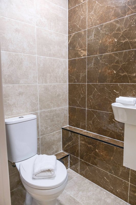 Modern bathroom with toilet, sink, and marble-effect tiled walls
