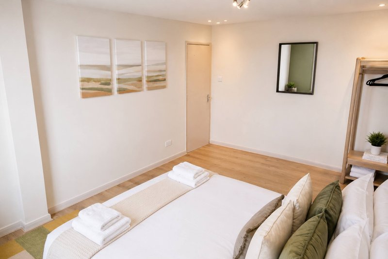 Bright bedroom with double bed, wooden floor, wall art, and mirror