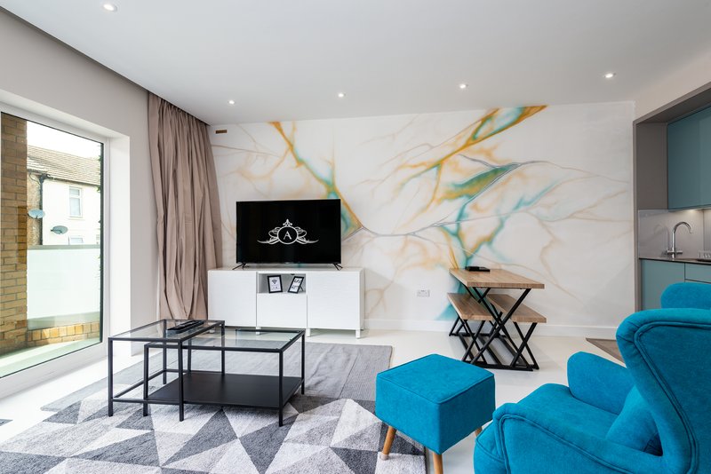Modern living room with blue armchairs, black coffee table, wall-mounted TV and marble feature wall