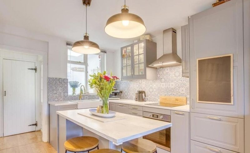 Modern kitchen with island, pendant lights, white cabinetry, and fresh flowers in vase