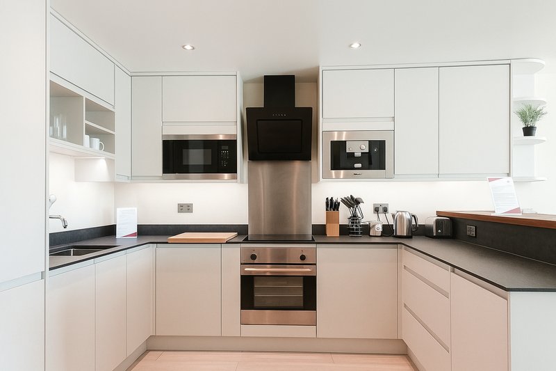 Modern kitchen with white and pink cabinetry, stainless steel appliances, and dark countertops