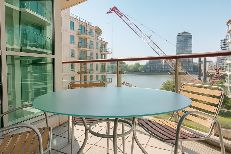 Waterfront balcony with round table, chairs, and city skyline view