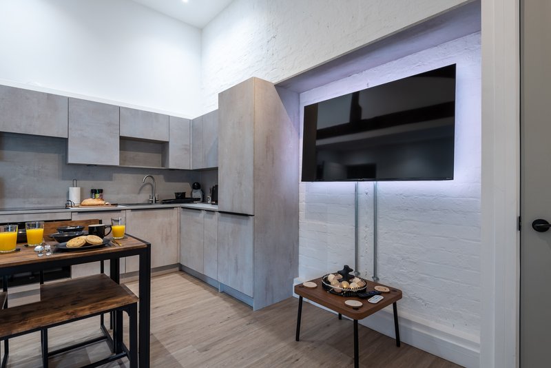 Modern kitchen with gray cabinetry, black countertops, dining table and yellow accessories
