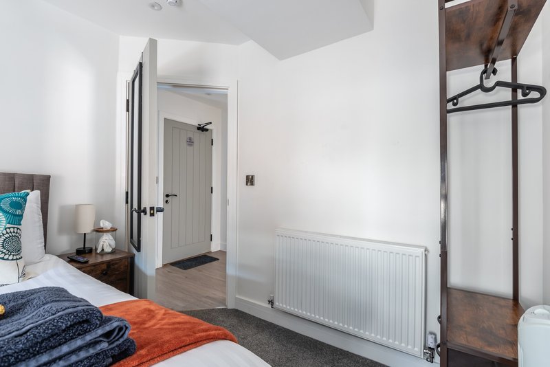 Bright bedroom with double bed, white walls, radiator, and wooden wardrobe