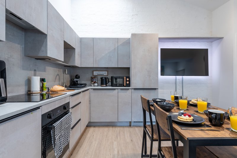 Modern kitchen with grey cabinetry, dining table set with plates and orange juice glasses