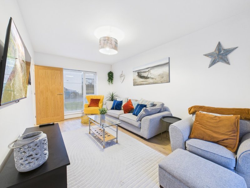 Bright living room with grey sofas, wooden door, wall art, and decorative star ornament