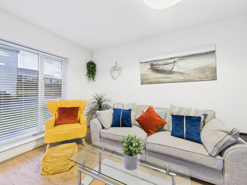 Bright living room with yellow armchair, gray sofa, colorful cushions and wall art