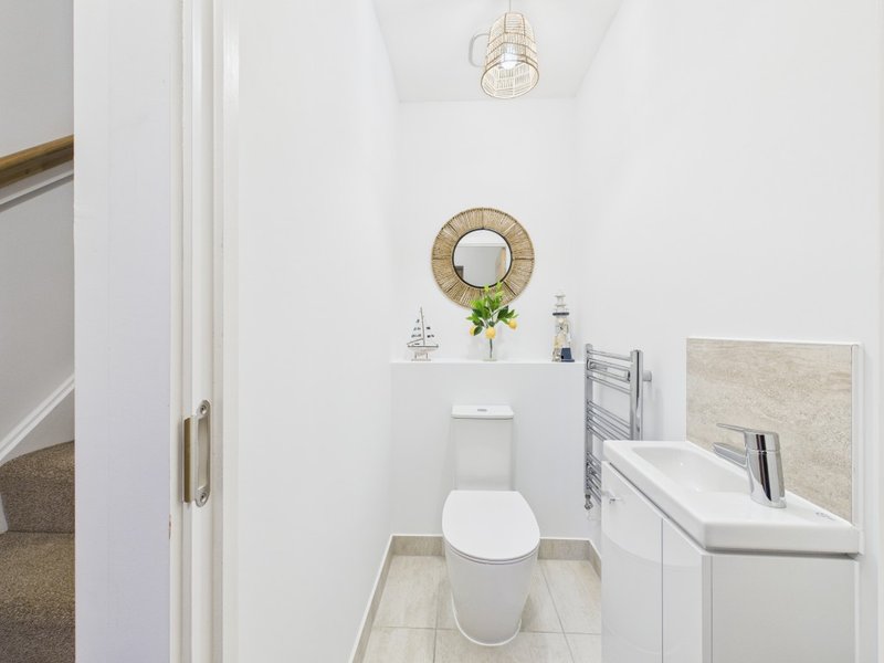 Modern bathroom with toilet, sink, mirror, and woven wall decor