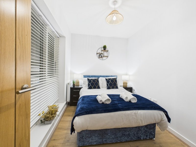 Modern bedroom with double bed, blue bedding, wooden door, and pendant light fixture