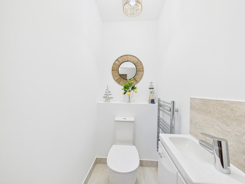 Clean white bathroom with toilet, sink, and decorative wall wreath