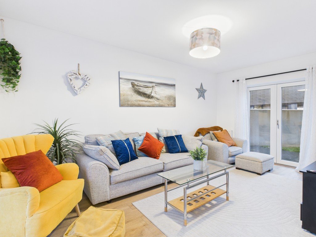 Bright living room with yellow armchair, grey sofa, colorful cushions and coffee table