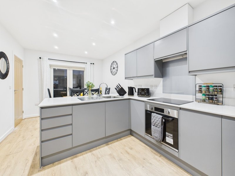 Modern kitchen with gray cabinetry, wooden flooring, stainless steel appliances and white countertops